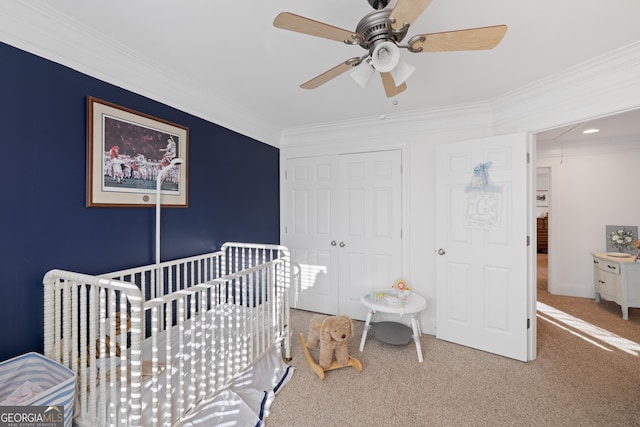 bedroom featuring ceiling fan, carpet, a nursery area, ornamental molding, and a closet