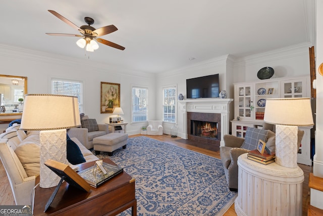 living room featuring ceiling fan, a fireplace, crown molding, and hardwood / wood-style flooring