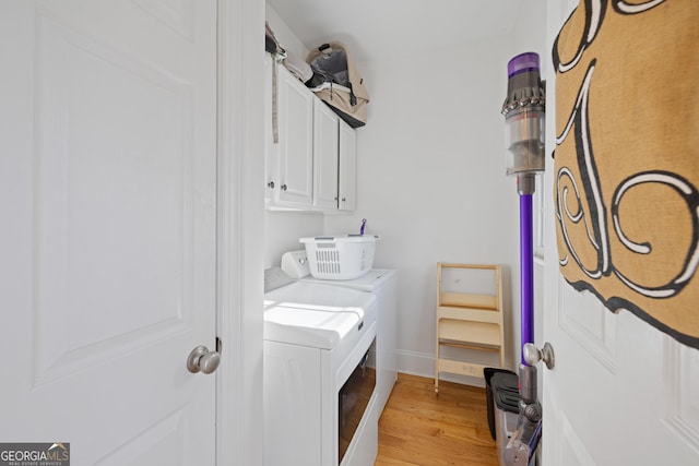 clothes washing area featuring cabinets, independent washer and dryer, and light hardwood / wood-style flooring