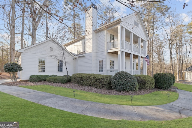 view of front of house featuring a balcony and a front yard