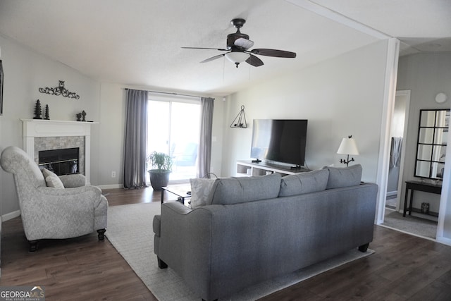 living room featuring ceiling fan, dark hardwood / wood-style floors, a tile fireplace, and lofted ceiling