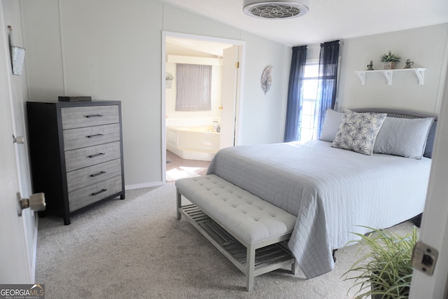 bedroom featuring light carpet, vaulted ceiling, and connected bathroom