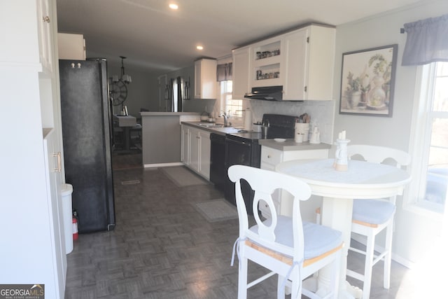 kitchen featuring a healthy amount of sunlight, decorative backsplash, white cabinets, dark parquet flooring, and black appliances