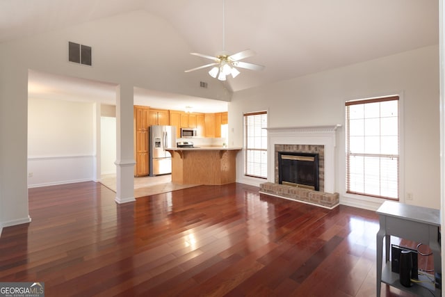 unfurnished living room featuring ornate columns, dark hardwood / wood-style flooring, ceiling fan, and a fireplace