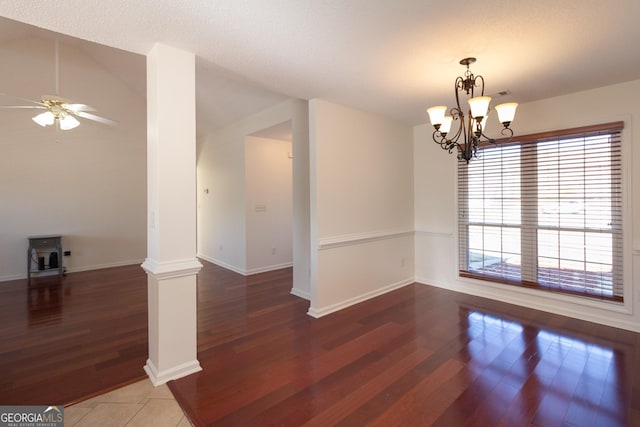 spare room with dark hardwood / wood-style flooring, ceiling fan with notable chandelier, and decorative columns