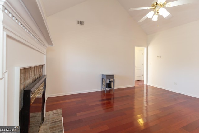 unfurnished living room featuring a brick fireplace, dark wood-type flooring, high vaulted ceiling, and ceiling fan