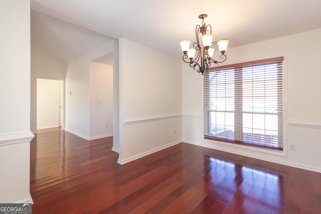 spare room with dark hardwood / wood-style flooring, a notable chandelier, and lofted ceiling