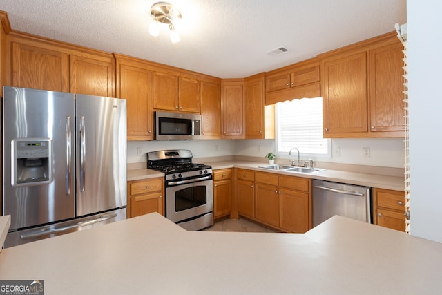 kitchen featuring appliances with stainless steel finishes, sink, and a textured ceiling