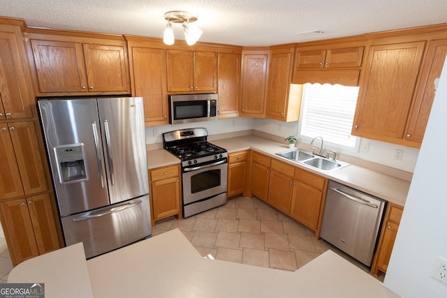 kitchen with stainless steel appliances, sink, a textured ceiling, and light tile patterned floors