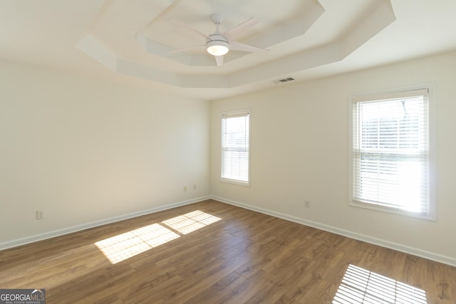 unfurnished room featuring hardwood / wood-style flooring, a raised ceiling, and ceiling fan