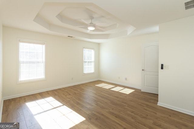 empty room featuring a tray ceiling, ceiling fan, and hardwood / wood-style flooring