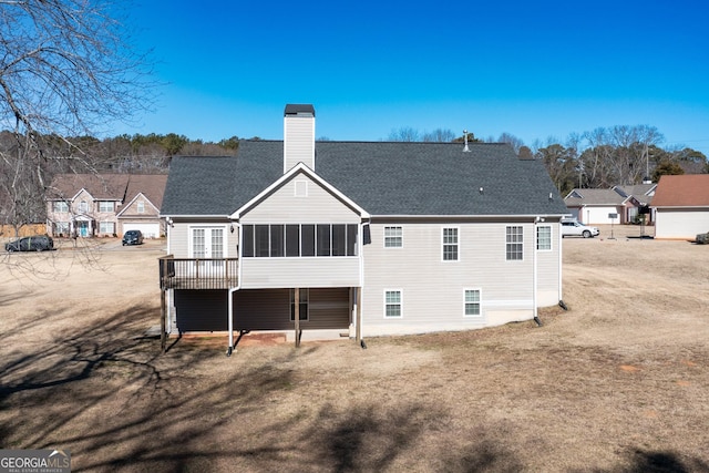 rear view of house featuring a yard and a sunroom