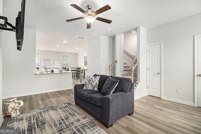 living room with ceiling fan, light hardwood / wood-style floors, and sink