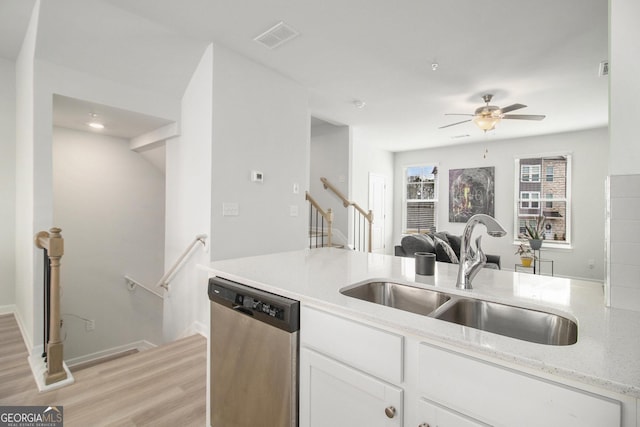 kitchen with light stone countertops, sink, white cabinets, and stainless steel dishwasher