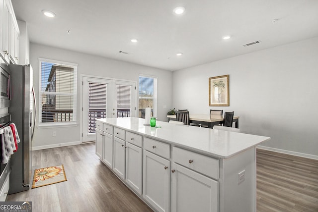 kitchen featuring hardwood / wood-style flooring, a kitchen island, stainless steel appliances, and white cabinets