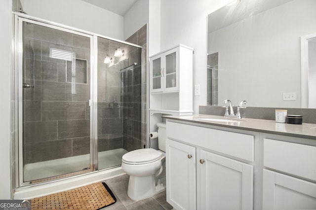 bathroom featuring a shower with shower door, toilet, vanity, and tile patterned flooring