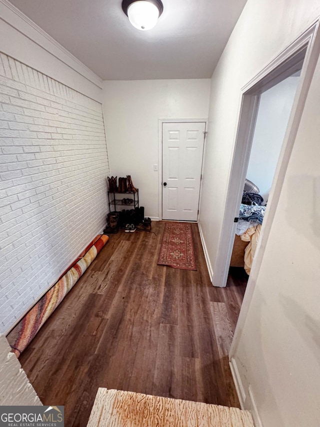 hall with ornamental molding, brick wall, and dark hardwood / wood-style flooring