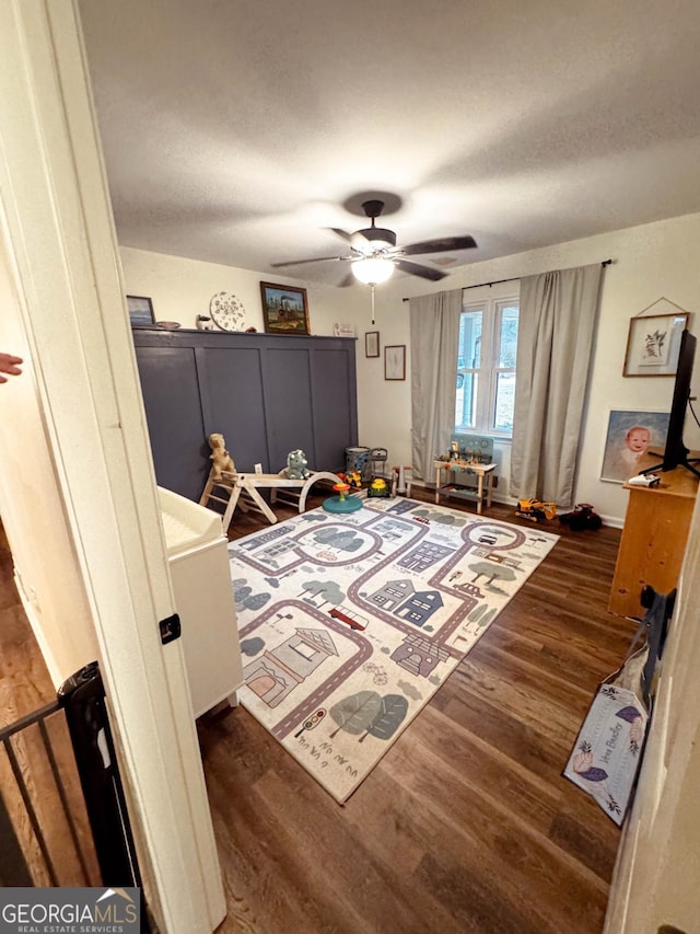 bedroom with dark wood-type flooring, a textured ceiling, and ceiling fan