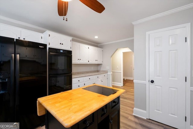 kitchen with a kitchen island, black appliances, crown molding, white cabinetry, and light wood-type flooring