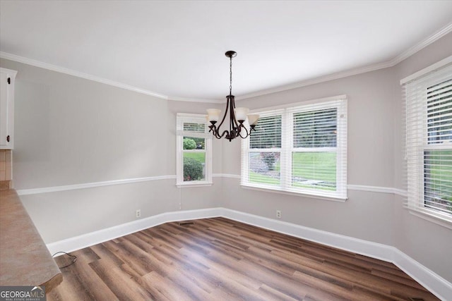 unfurnished dining area featuring hardwood / wood-style flooring, ornamental molding, and a chandelier