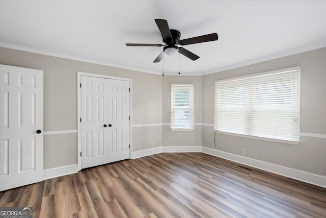 unfurnished bedroom featuring ceiling fan, a closet, dark hardwood / wood-style flooring, and ornamental molding