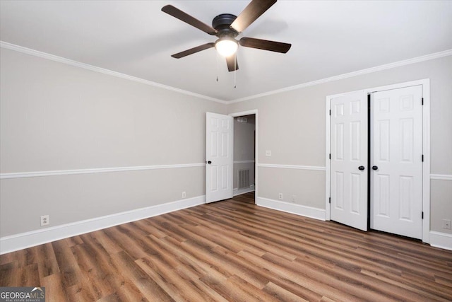 unfurnished bedroom with dark wood-type flooring, ceiling fan, crown molding, and a closet