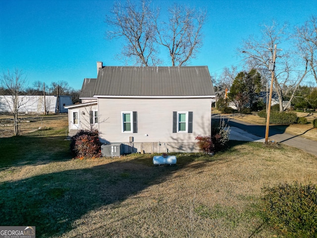 rear view of house featuring cooling unit and a lawn