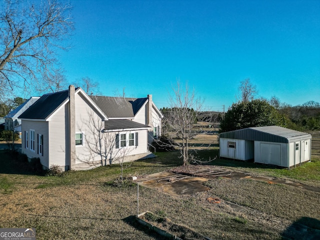 back of property featuring a lawn and an outdoor structure