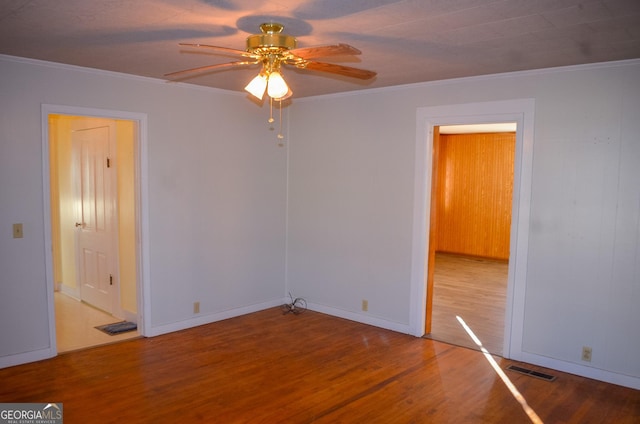 empty room with ceiling fan, wood-type flooring, and ornamental molding