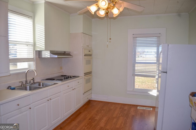 kitchen with white appliances, white cabinetry, light hardwood / wood-style floors, sink, and ornamental molding