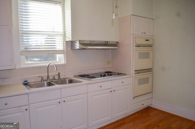 kitchen featuring white cabinets, stovetop, double oven, sink, and light hardwood / wood-style flooring