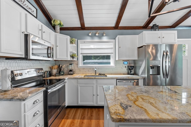 kitchen with light stone countertops, appliances with stainless steel finishes, white cabinetry, and sink