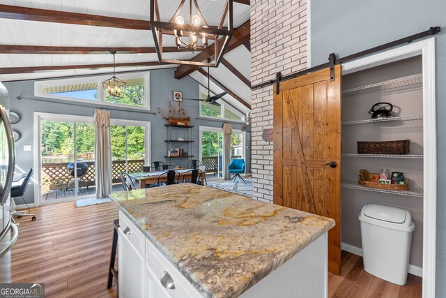 kitchen featuring decorative light fixtures, a barn door, beamed ceiling, an inviting chandelier, and white cabinets