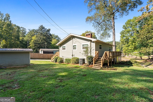 rear view of house featuring a deck, a yard, and central AC unit