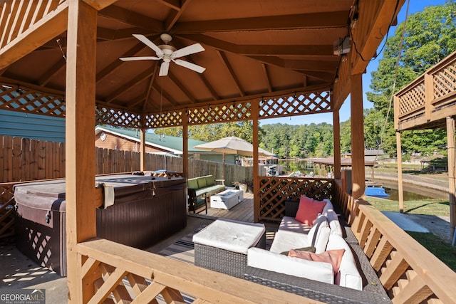 wooden terrace featuring ceiling fan, a gazebo, a hot tub, and an outdoor living space