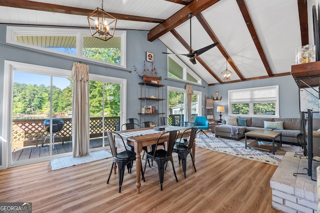 dining area featuring high vaulted ceiling, beam ceiling, ceiling fan with notable chandelier, and light hardwood / wood-style flooring