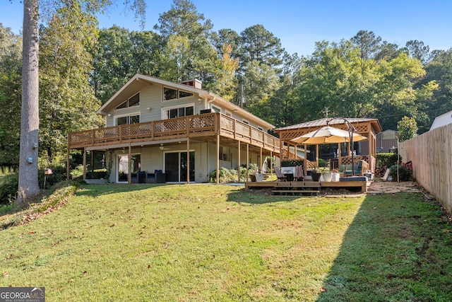 back of property featuring a wooden deck, a gazebo, and a yard