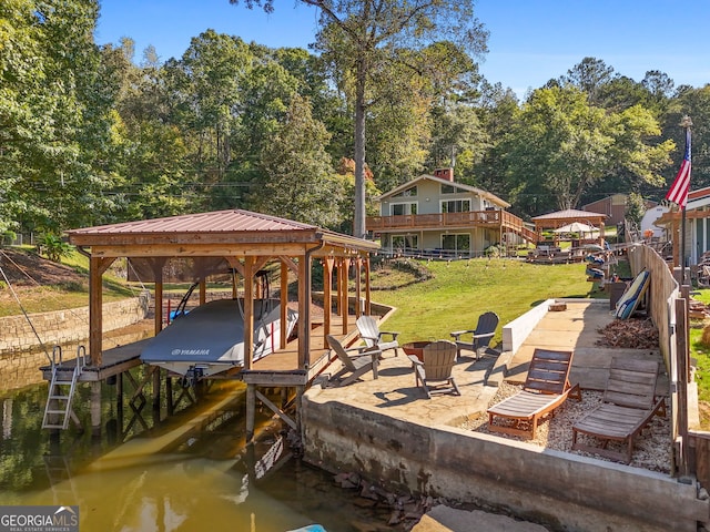 dock area with a water view, an outdoor fire pit, and a lawn