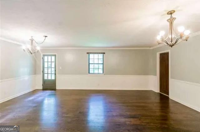 spare room with dark hardwood / wood-style flooring, ornamental molding, and a notable chandelier