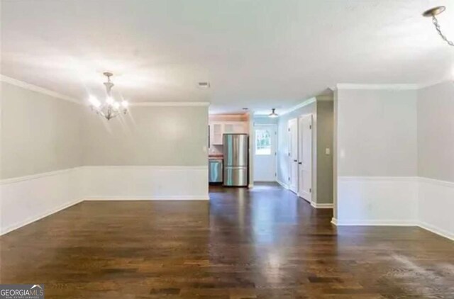 empty room featuring dark hardwood / wood-style floors, ornamental molding, and an inviting chandelier