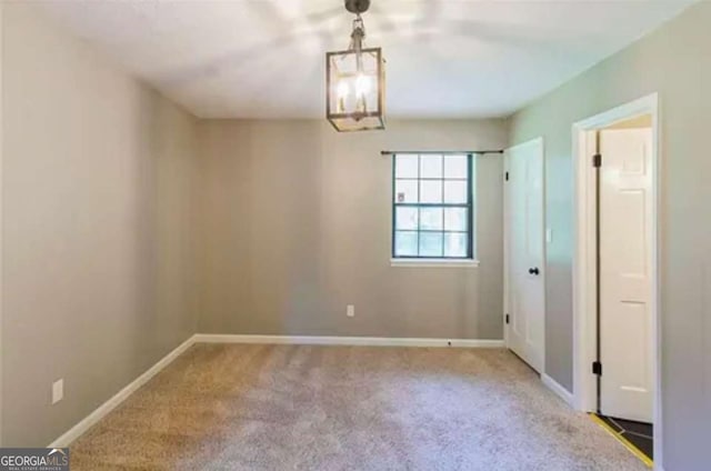 carpeted empty room with an inviting chandelier