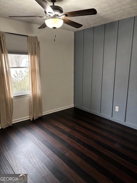 unfurnished room featuring ceiling fan, dark hardwood / wood-style floors, and a textured ceiling