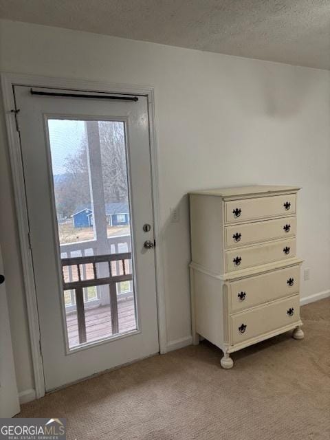 doorway to outside with light colored carpet and a textured ceiling