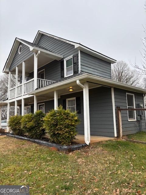 view of side of property with a lawn and a balcony