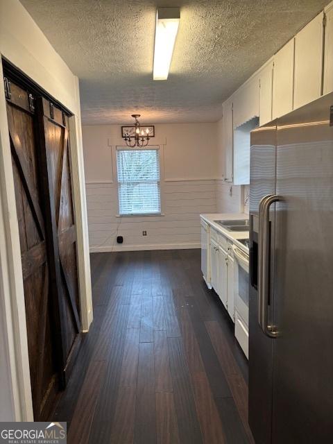 kitchen featuring stove, an inviting chandelier, white cabinetry, stainless steel fridge with ice dispenser, and dark hardwood / wood-style flooring