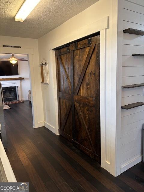 hall featuring a textured ceiling, dark hardwood / wood-style flooring, and a barn door