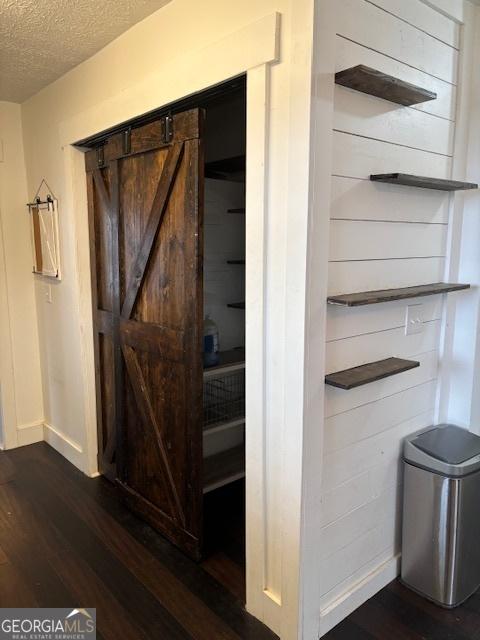 interior space with a barn door, a textured ceiling, and hardwood / wood-style flooring