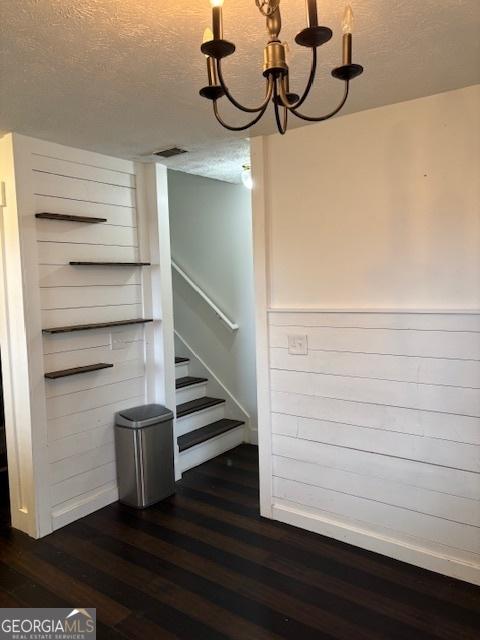 staircase featuring a textured ceiling, hardwood / wood-style floors, and an inviting chandelier