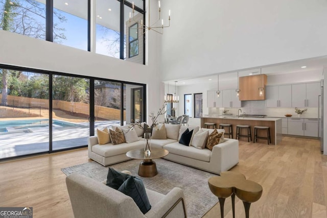 living room with light wood-type flooring, a high ceiling, and a notable chandelier