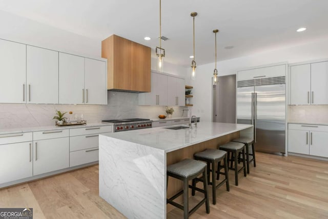 kitchen with pendant lighting, a center island with sink, sink, appliances with stainless steel finishes, and white cabinets